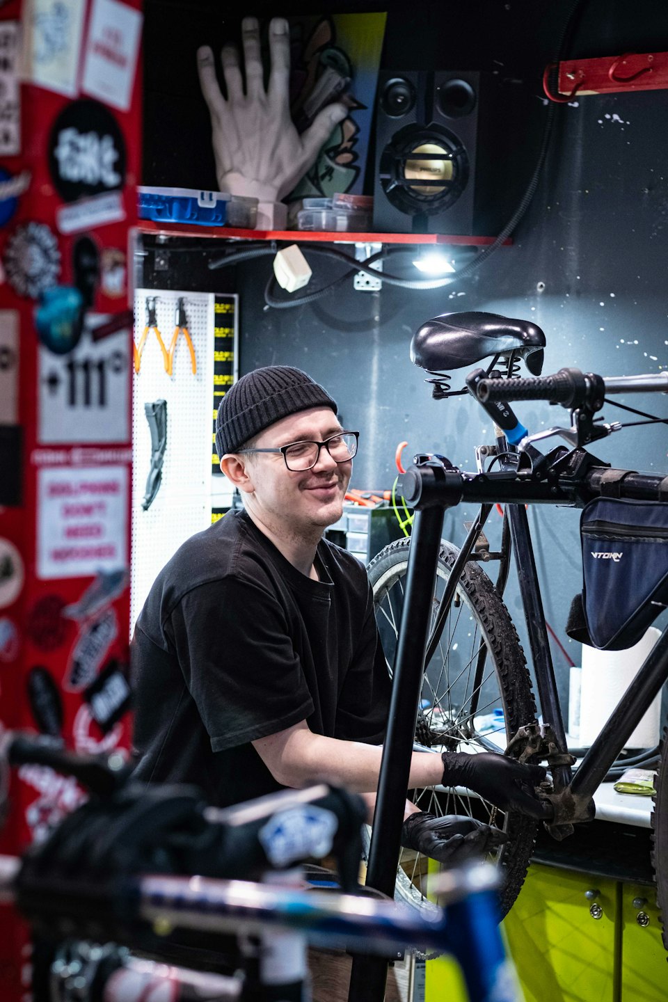 Man med mössa och handskar reparerar cykelns bakhjul.
